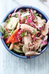 Tuna salad with tomatoes, cannelloni bean and endive. Bright wooden background. Top view. Close up.