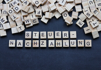 Holzbuchstaben auf Tafel, Steuernachzahlung