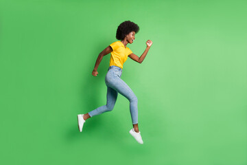 Fototapeta na wymiar Full body profile side photo of brunette wavy haired dark skin lady jump up run wear jeans isolated on green color background