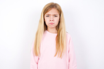 beautiful caucasian little girl wearing pink hoodie over white wall crying desperate and depressed with tears on his eyes suffering pain and depression. Sad facial expression and emotion concept.