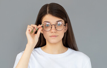 Attrative trendy young woman with eyeglasses, isolated on gray background