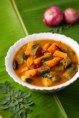 Sambar , Lentil sambar mixed vegetable curry soup for Onam sadhya vishu spicy hot isolated on green banana leaf. popular south Indian food in Kerala Tamil Nadu Sri lanka