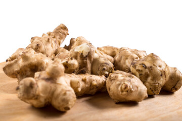 Roots of Jerusalem artichokes close up. Tubers od Jerusalem artichokes on a wooden table.