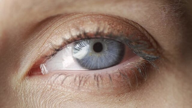close up macro blue eye opening human iris natural beauty.