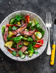 Potato, beef steak, romano and vegetable salad on a dark background, top view. Balanced diets healthy food