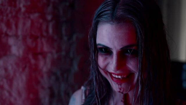 A girl in a white bloody sundress, looking like a dead man, grins - Halloween costume party