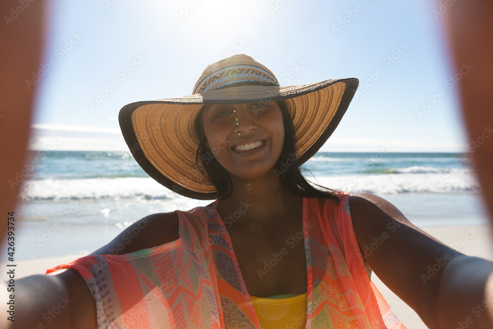 Wall mural Smiling mixed race woman on beach holiday taking selfie