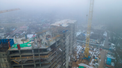 Tall construction crane in the fog. Construction buiding in the mist. Industry concept.
