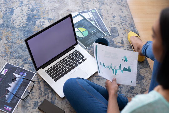 Mixed race gender fluid man working at home sitting on floor using laptop, copy space screen