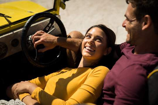 Happy caucasian couple sitting in beach buggy by the sea relaxing