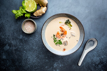 Tom Yum Kung soup, a Thai traditional spicy prawn soup in a bowl on gray background, top view