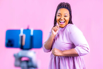 hispanic woman with cool dreadlocks pigtails wear pink dress in studio chatting with her subscribers by phone camera