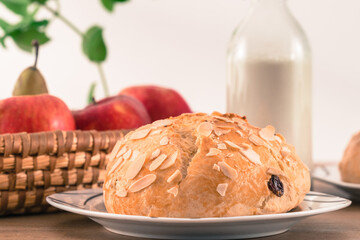 Freshly baked, homemade sweet cake with almonds and raisins on wooden table. Easter loaf. Basket with pears and apples. Vintage bottle of milk.