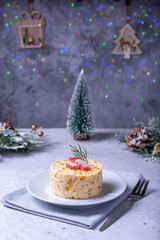 Crab salad with corn and eggs on a white plate. New Year's and Christmas. Traditional Russian salad. Close-up. In the background there are Christmas decorations and bokeh.