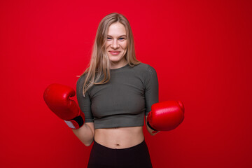 Sporty young woman in red boxing gloves having fun