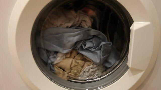 A clothing mix rotation leveling in front loaded wash machine can closeup, household washing
