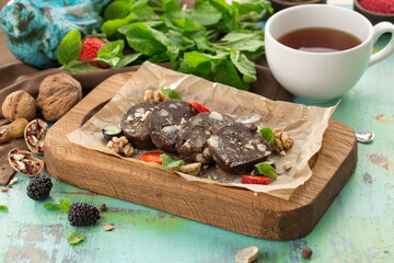 Delicious chocolate roll cake with nuts and cup of tea on the table