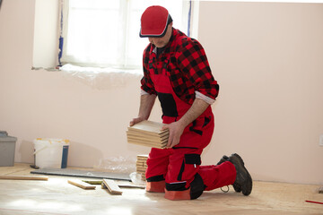 Handyman installing wooden flooring, Worker laying parquet flooring. Worker installing wooden laminate flooring. Parquet and carpenter concept,