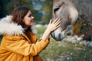 woman in nature jacket next to donkey animal friendship travel