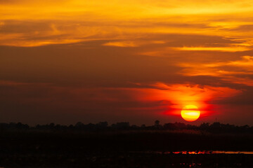 Landscape photo of big sun at sunset or evening time over the lake.