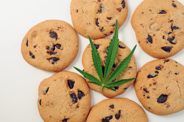 Sweets with CBD oil. Marijuana leaf on white background. Cannabis oil and chocolate cookies close-up. Top view, flat lay.