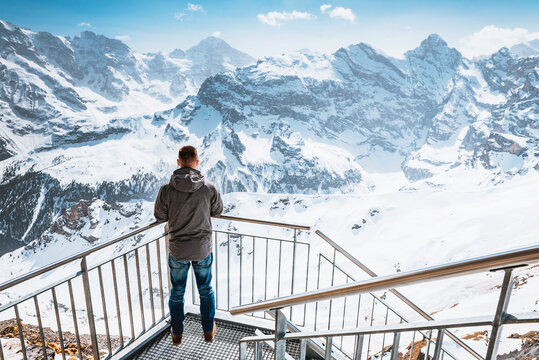 A young man looks at the Swiss Alps at the beginning of a sky walk from the top of Birg