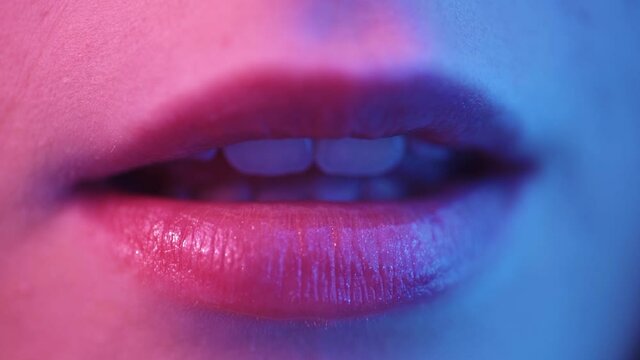 Beauty sexy model lips close-up, disco. Woman mouth closeup. Metallic lipstick makeup. Purple and blue ultraviolet lights. Slow motion UHD video.