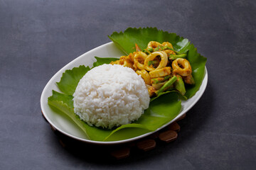 Squid curry paste with steamed rice in a white plate on a black table