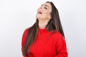 young beautiful brunette woman wearing red knitted sweater over white wall suffering from strong stomachache.