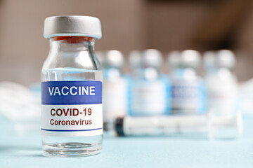 Macro shot of antiviral vaccine vial with syringe for immunization against covid-19 virus. Blurred out background with copy space for text. Close up, top view.