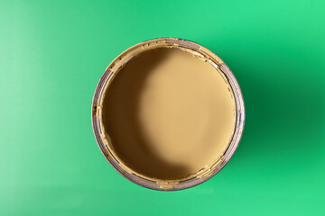 Can with paint of yellow color on green background.