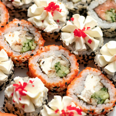 Sushi rolls decorated with sesame seeds and masago or tobiko caviar. Inside-out Sushi Set. Different types of rolls. Asian or Japanese food, Oriental cuisine. Close up shot. Top view. Soft focus.