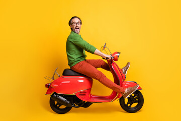 Fototapeta na wymiar Photo of careless guy ride motorcycle have fun wear specs green sweater trousers footwear isolated yellow color background