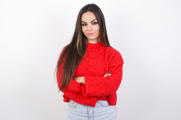 Honest young beautiful brunette woman wearing red knitted sweater over white wall keeps hands on...