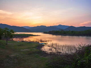 beautiful landscape hills and meadow with orange sky reflection in water. mountain lake in the sunset.