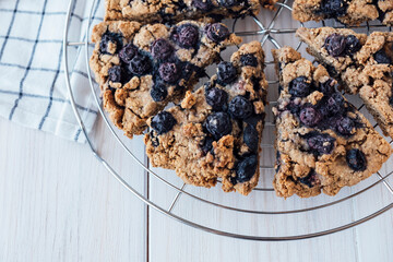 Freshly baked oat blueberry scones on cooling rack on white wooden background. Vegan and plant...