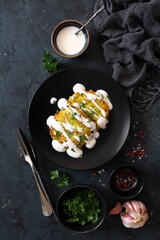 Potato pancakes with zucchini served with sour cream on dark table. Top view with copy space.