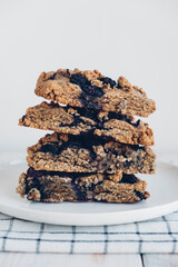 Stack of freshly baked oat blueberry scones on white plate, close up. Sweet food with natural ingredients. Vegan gluten free pastry.