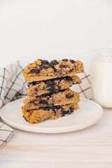 Stack of homemade oatmeal scones with berries stacked on white plate and glass of plant based milk. Vegan sweet baked food. Gluten free pastry. Healthy breakfast.
