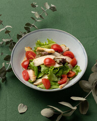 Fresh salad with chicken fillet or breast, lettuce and tomatoes. Holiday or festive vitamin dish with meat, vegetables and greens. Nicely served food plate on restaurant table. Top view.