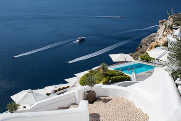 Perfect view of Santorini: swimming pool in luxury hotel, yachts and Mediterranean sea.