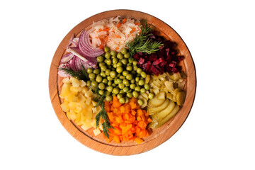 Sliced vegetables are on a round wooden plate. Boiled potatoes, carrots, beets, pickles, red onions, green peas, sauerkraut, dill sprigs. Salad ingredients. Vegetarianism, diet, lean food. Isolated.