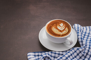 A white cup of coffee and cloth placed on the old kitchen table. Top view with copy space for your text. Concept of the morning, energy, and cheerfulness