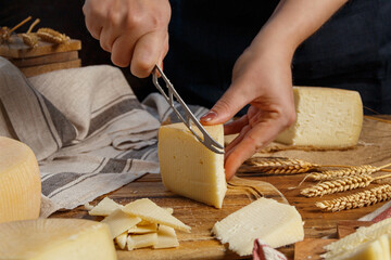 Somebody hands cut a piece of  fresh homemade cheese on a wooden board