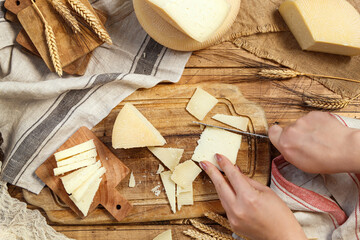 Hands cut pieces of  fresh homemade cheese on a wooden board