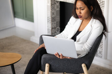 a focused black woman in a suit is working on a laptop. Remote work from home