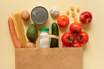 Grocery, food stuff in the paper shopping bag on the creamy color background.