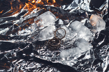 Wedding rings with splashes of water, pieces of ice and lights. Wedding concept