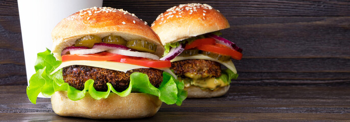 Banner Cheeseburger on a cutting board and cup of coffee on a wooden background. Hamburger with cheese. Burger isolated. Tasty dinner