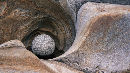 Close-up of one round stone on grey granite stone waves made by crystal clear water. Garden and zen concept. Symbol of stability and natural world.